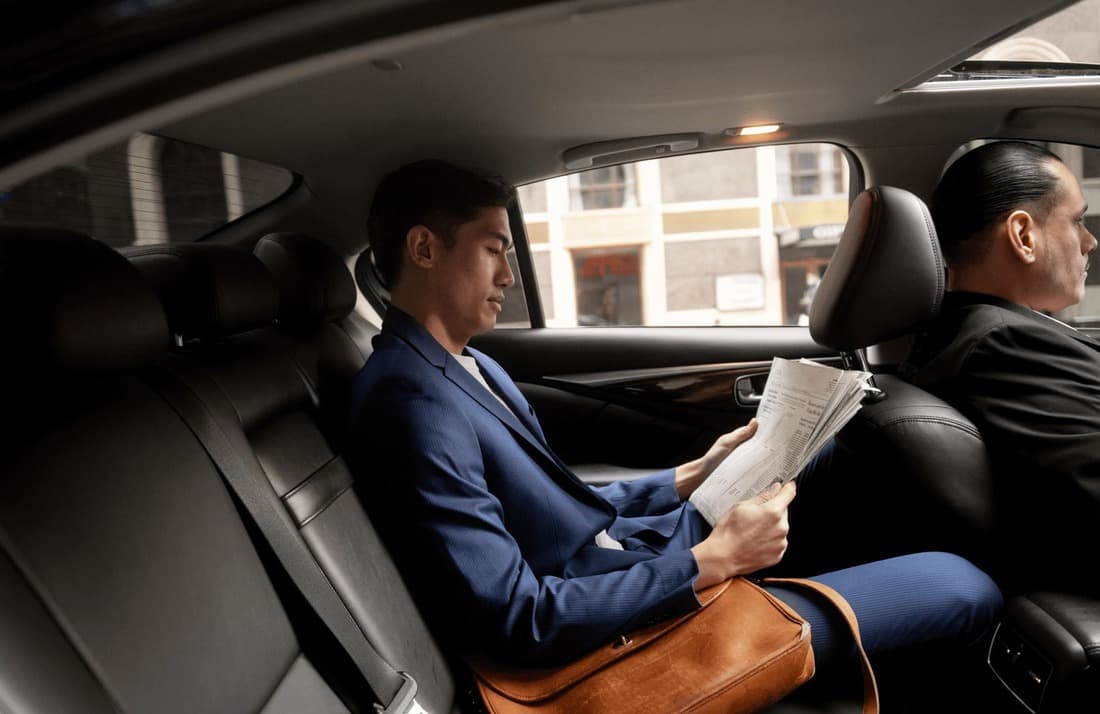 Man in back seat reading newspaper